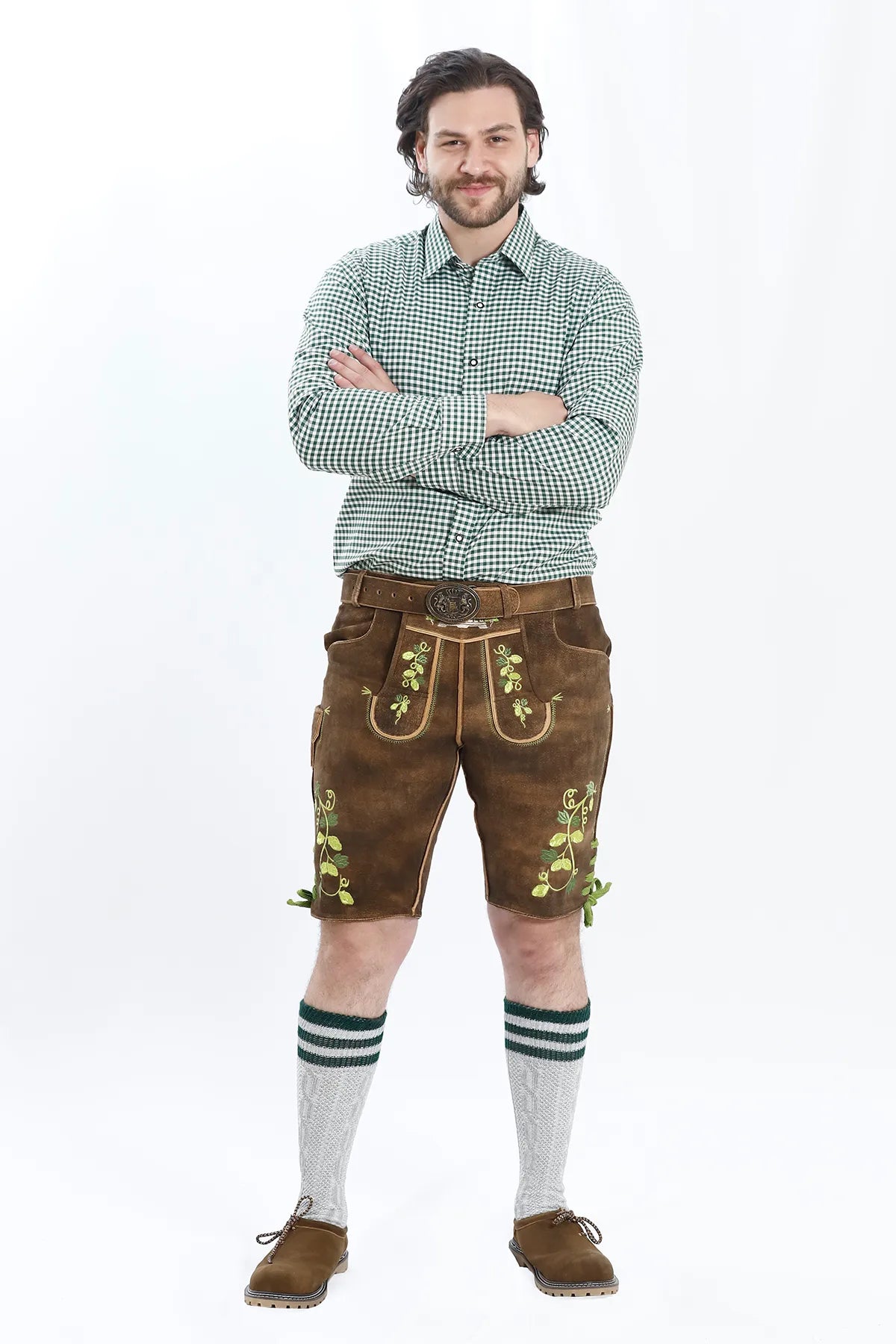 Lederhosen Men in Brown Color with Traditional Green Embroidery. Model is wearing checkered green shirt and Traditional Bavarian Shoes.